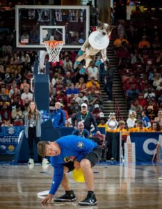 Dog in booties leaps for a disc as the crowd watches